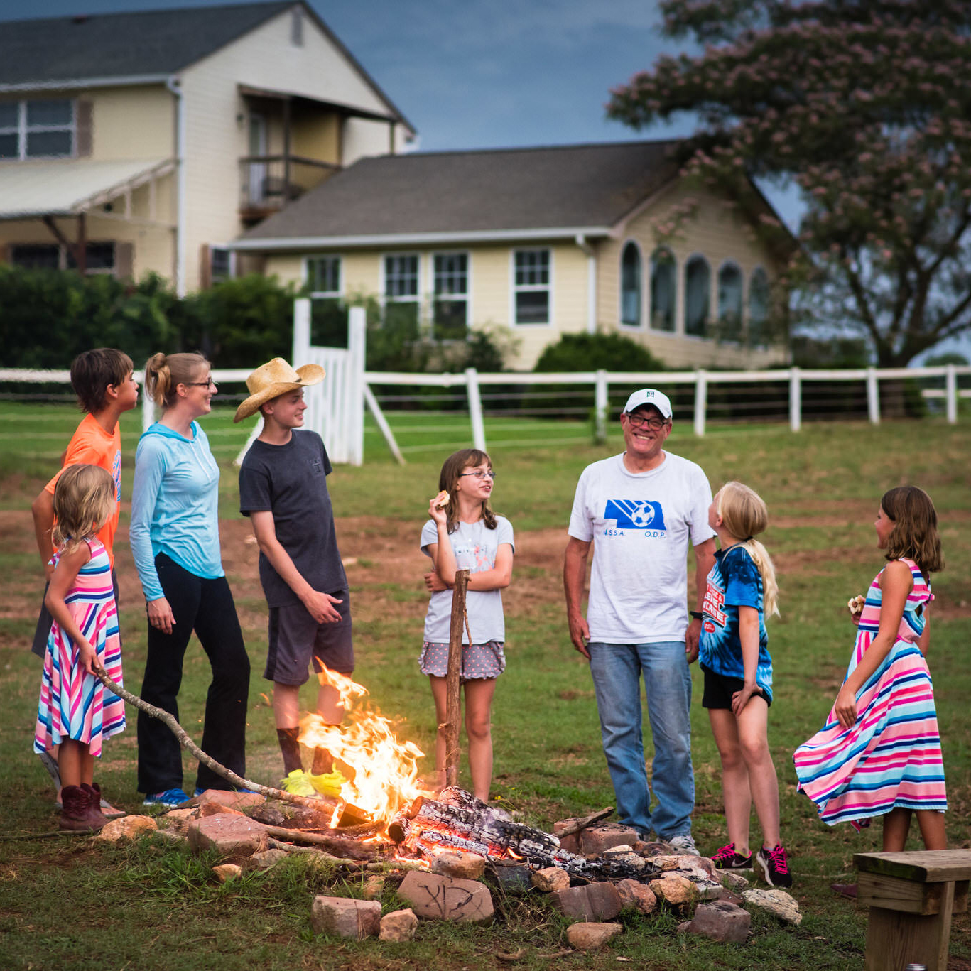 family laughing by fire pit at ranch